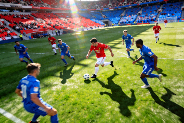 英超足球比赛现场，球员正在带球突破，绿茵场全景